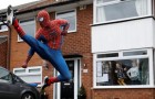 Två vänner klär ut sig till Spiderman och hälsar på barn i ett kvarter som är isolerat på grund av covid-19