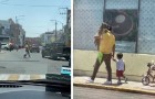 Man walks along the street with his dog in his arms like a baby, while his little son walks alongside
