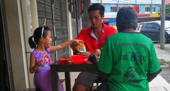 Un padre y su hija invitan a un indigente hambriento a comer en la mesa con ellos