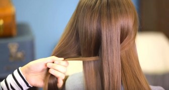 Hon delar upp håret i två lika delar och flätar dem tillsammans: resultatet är väldigt proffsigt