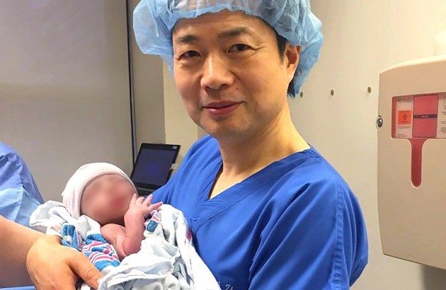 Il dottor John Zhang tiene in braccio il bambino nato da questa tecnica nell'aprile 2016.