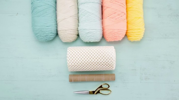 Buy some skeins of yarn, in any color that you prefer, also have on hand a pair of scissors, an anti-slip rug canvas, and a finished cardboard paper roll.