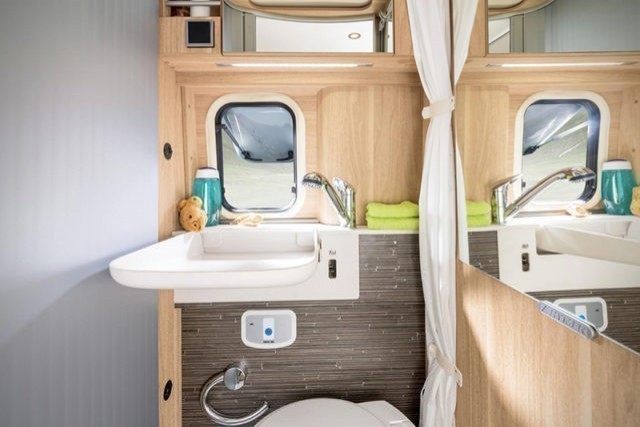 De badkamer is compact met een verstelbare wastafel en een ruimtebesparend toilet.