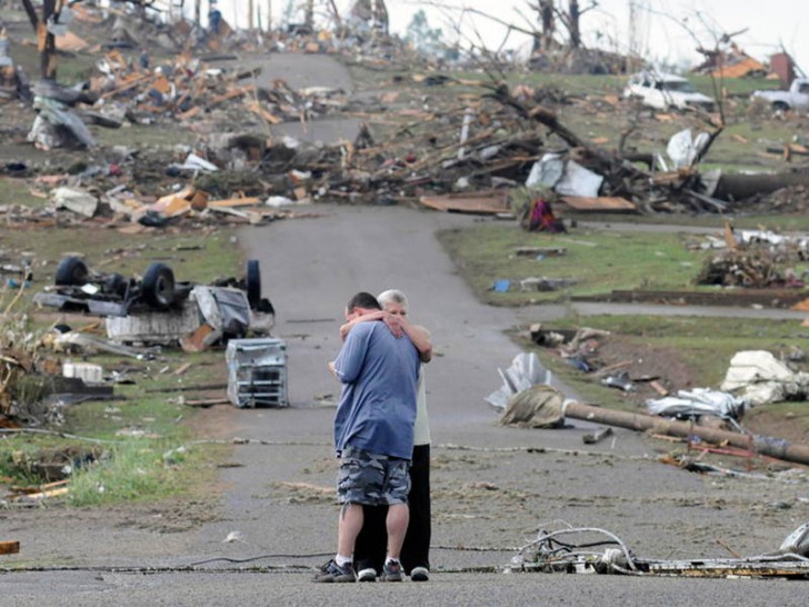 4. Alcuni membri di una famiglia si abbracciano sullo sfondo delle devastanti conseguenze del tornado Alabama (Marzo 2012).