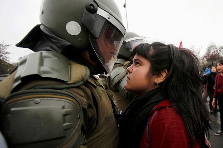 Een demonstrante kijkt iemand van de Chileense ME strak aan. Hij is er klaar voor om de protesten de kop in te drukken. Chili 11 september 2016