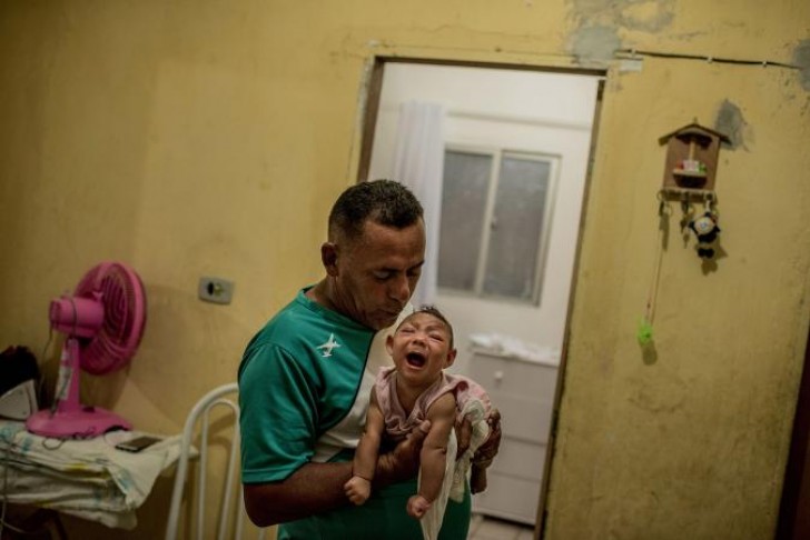 1. Un padre si prende cura della figlia affetta da microcefalia. La piccola deve assumere più di 28 medicinali al giorno e la famiglia non dispone di supporto economico statale (Brasile).