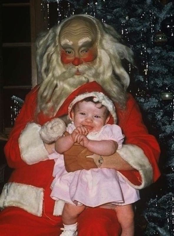 Ook al lijkt dit meer een wassen masker dan het toonbeeld van kerst, dit meisje in zijn armen vermaakt zich!