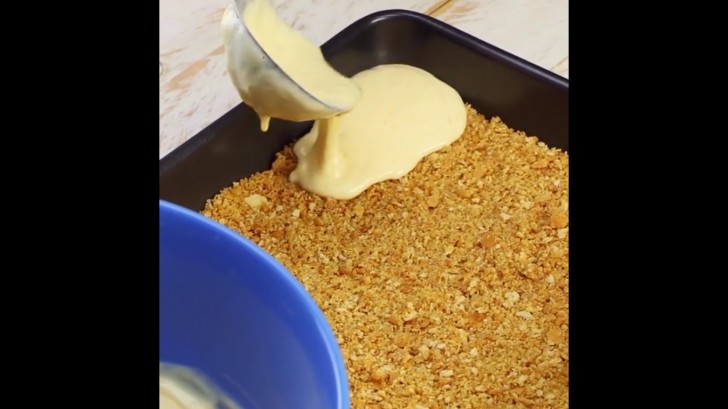 Spargete la granella di biscotti sul fondo di una teglia quadrata, aggiungete il composto di formaggio e cuocete il tutto a 160°C per 30 minuti.