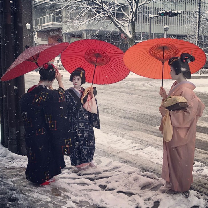 Donne in abito tradizionale passeggiano con stupore tra le strade innevate.