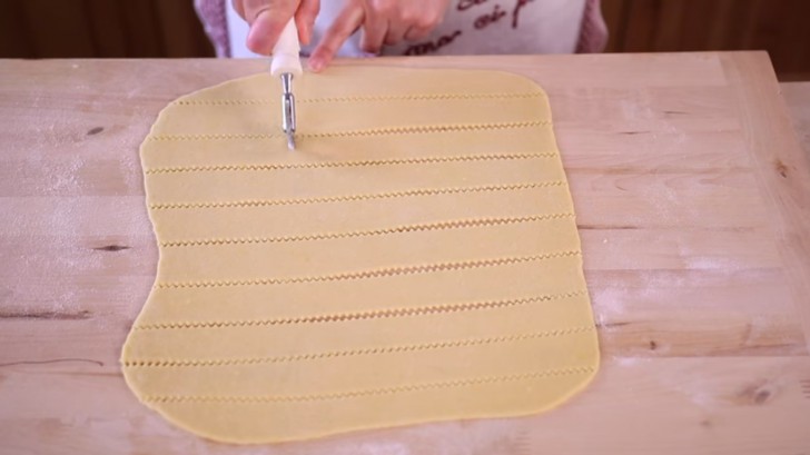 With a toothed dough cutter wheel create strips of dough.