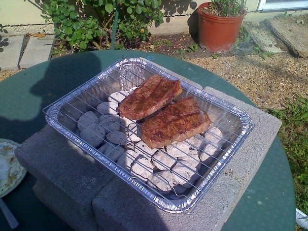 Make a last-minute barbecue grill with just an aluminum pan, a metal grill rack and a few stones.