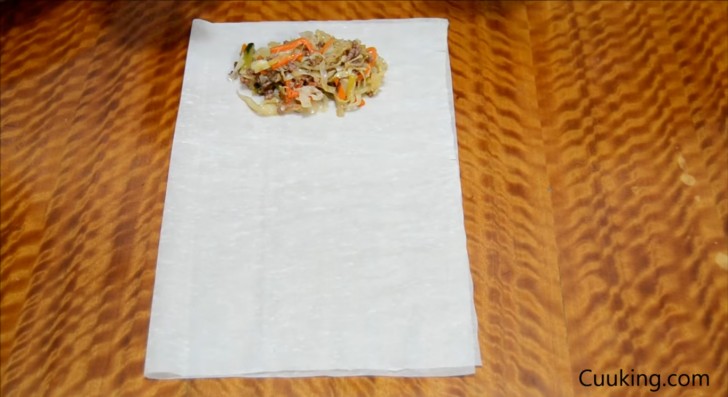 Fold half a sheet of rice pasta and put two tablespoons of vegetable mix in the center near the edge.