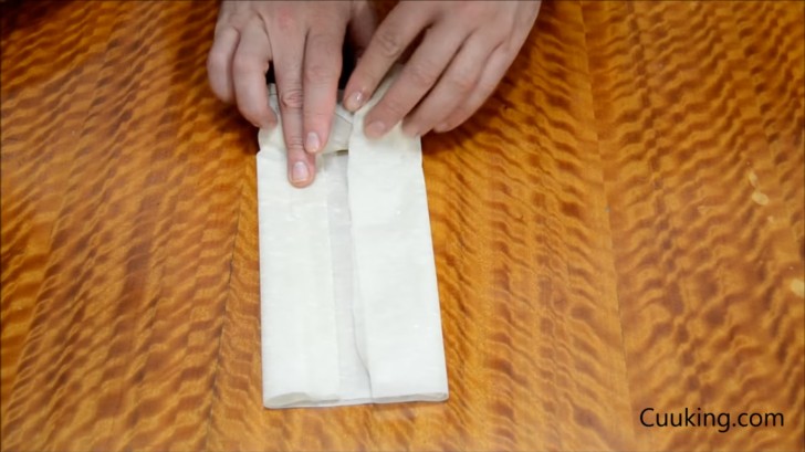 Commencez à enrouler le rouleau, puis fermez les bords vers l'intérieur et continuez à envelopper la pâte filo jusqu'à la fin.