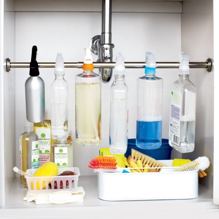11. In the space under the kitchen sink, attach an extendable rod so that you can hook all the spray bottles of the products used most often on it.