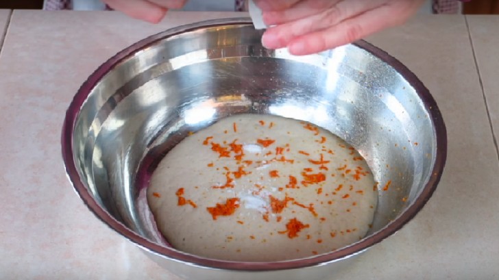 In una ciotola più grande versare il lievito, grattugiare la scorza d'arancia e aggiungere la bustina di vanillina.