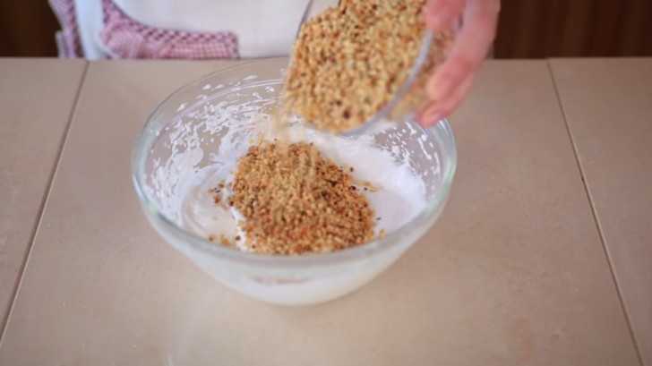 2. Pour the finely chopped hazelnuts into the mounted egg whites, a little at a time, using a spatula, mixing from bottom to top.
