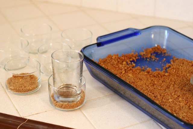 1. Mettere due cucchiai della base biscotto in un bicchiere dal fondo largo e schiacciare con uno più stretto.