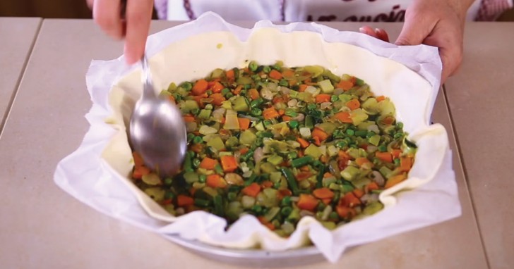 3. Preparate una teglia tonda e adagiate all'interno un rotolo di pasta sfoglia, poi versate le verdure cotte.