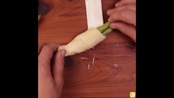 Cut out strips of dough about 3 cm (1.18 in) wide from the pastry sheet and roll them around two asparagus.