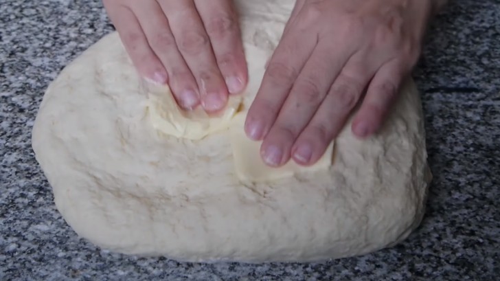 Continuer le pétrissage sur le plan de travail: quand la pâte sera élastique et molle, travaillez-la avec la moitié du beurre nécessaire.
