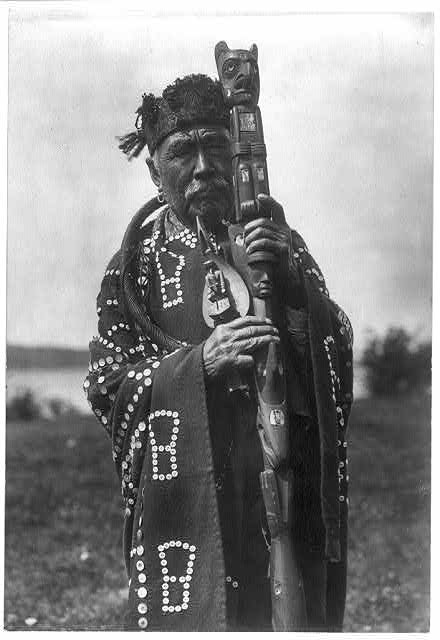8. Un chef Kwakiutl alors qu'il porte ses instruments rituels: le manteau, le bâton et le hochet chamanique.