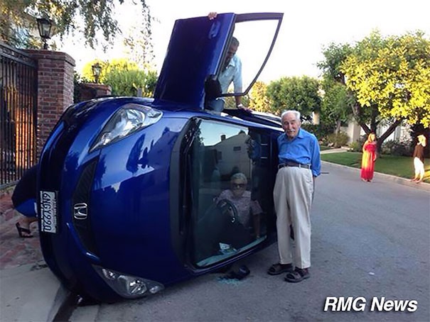 Si sono appena ribaltati con l'auto e la moglie è ancora incastrata all'interno, ma lui sorride... In fondo non si è fatto male nessuno!