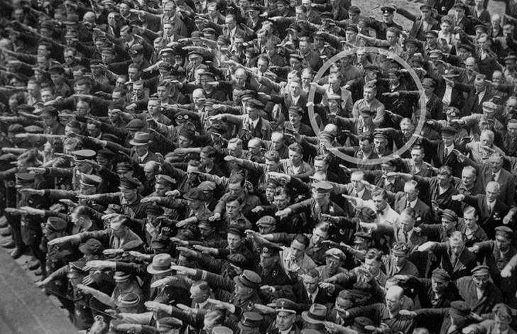 Un homme refuse de faire le salut nazi lors d'un défilé militaire en Allemagne en 1936.