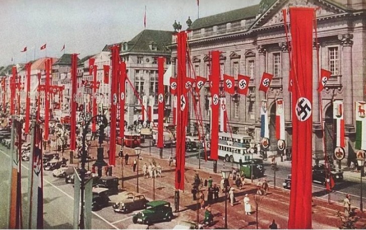 Ein nachcoloriertes Foto einer deutschen Stadt, bereit für eine Nazi-Parade (30er Jahre).