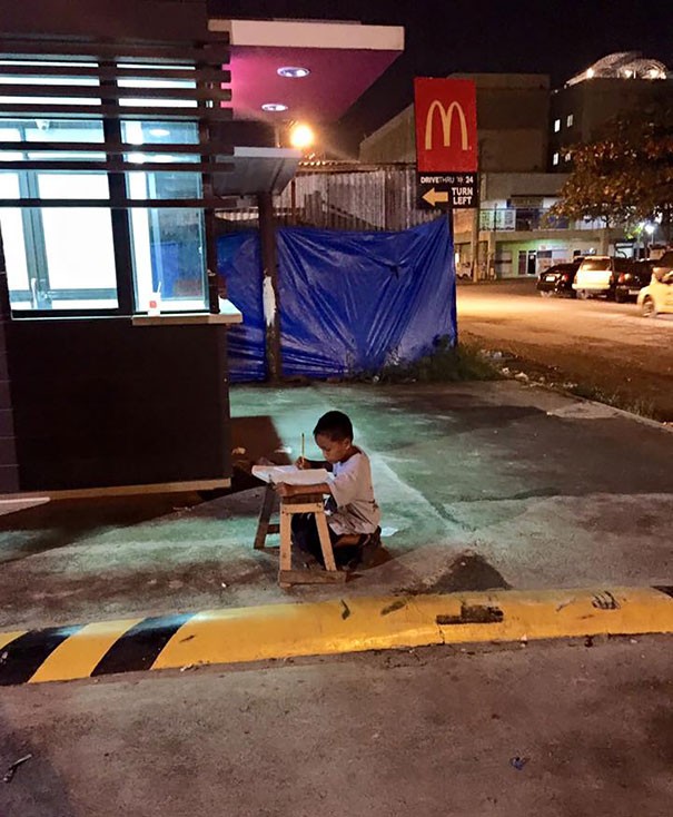 Cet enfant n'a pas d'électricité à la maison, alors le soir, il va faire ses devoirs à la lumière d'un réverbère près de la route.