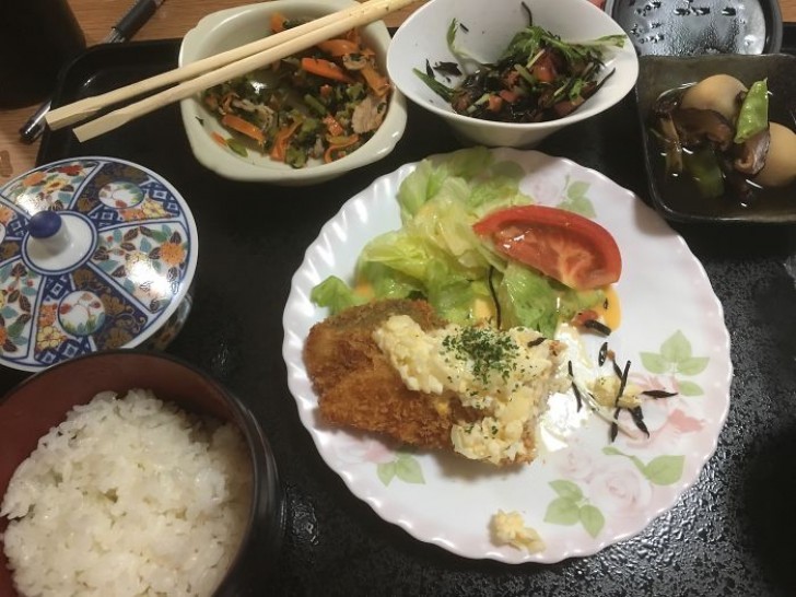 Pesce impanato su letto di insalata, patate, insalata giapponese, spinaci e carote al vapore, riso e tè verde