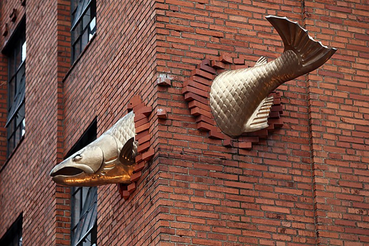 "Transcendence", ein Werk von Keith Jellum das einen fliegenden Lachs darstellt, der an einer Hausecke in der Southwest Salmon Street zur Southwest Park Avenue vor sich hin zappelt (Portland, USA).