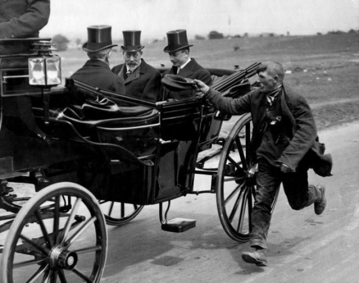 Een man haalt het rijtuig van de Engelse koning George V in, om hem aalmoezen te vragen.