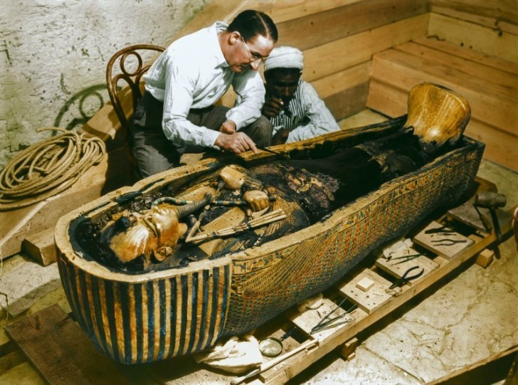Carter en een arbeider onderzoeken de binnenkant van de kist, gemaakt van puur goud