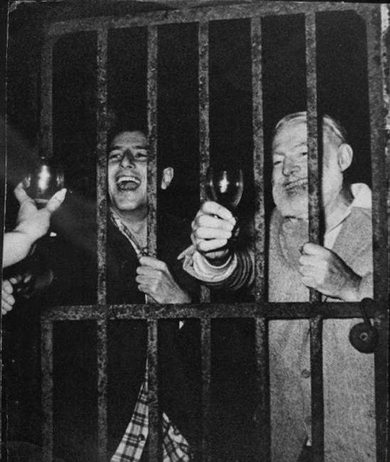 A rare photo of Ernest Hemingway and Spanish matador, Antonio Ordonez, drinking and laughing behind bars in Spain. (August, 1959)