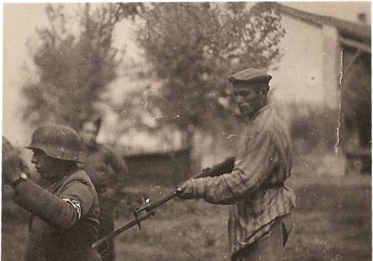 Ein ehemaliger Gefangener des Konzentrationslagers zielt mit dem Gewehr auf einen Soldaten der Nazis.