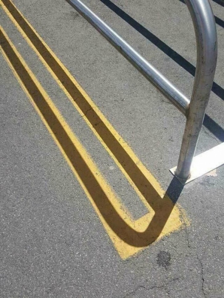 19. The shadow of the handrail falls precisely within the lines on the asphalt.