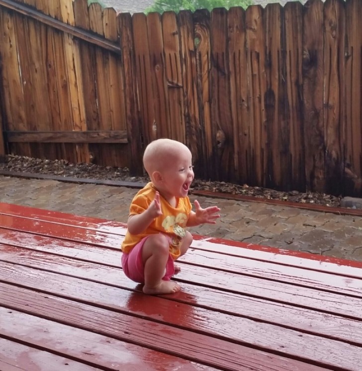 Esta pequeña niña siente la lluvia sobre su piel por primera vez.