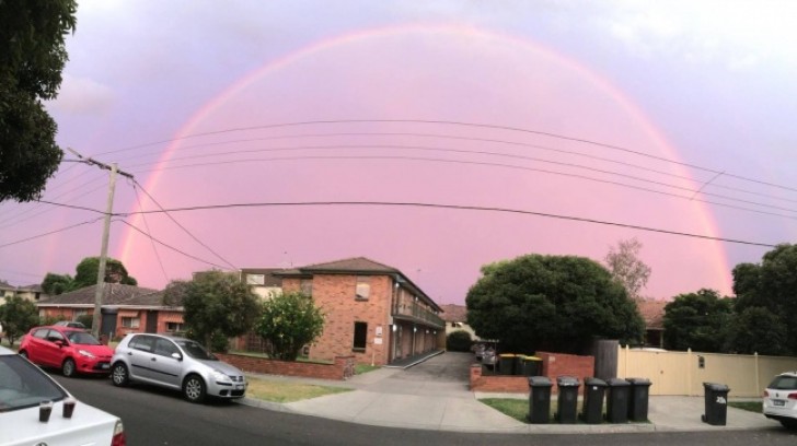 A 180° rainbow seems to form a protective shield over this neighborhood block!