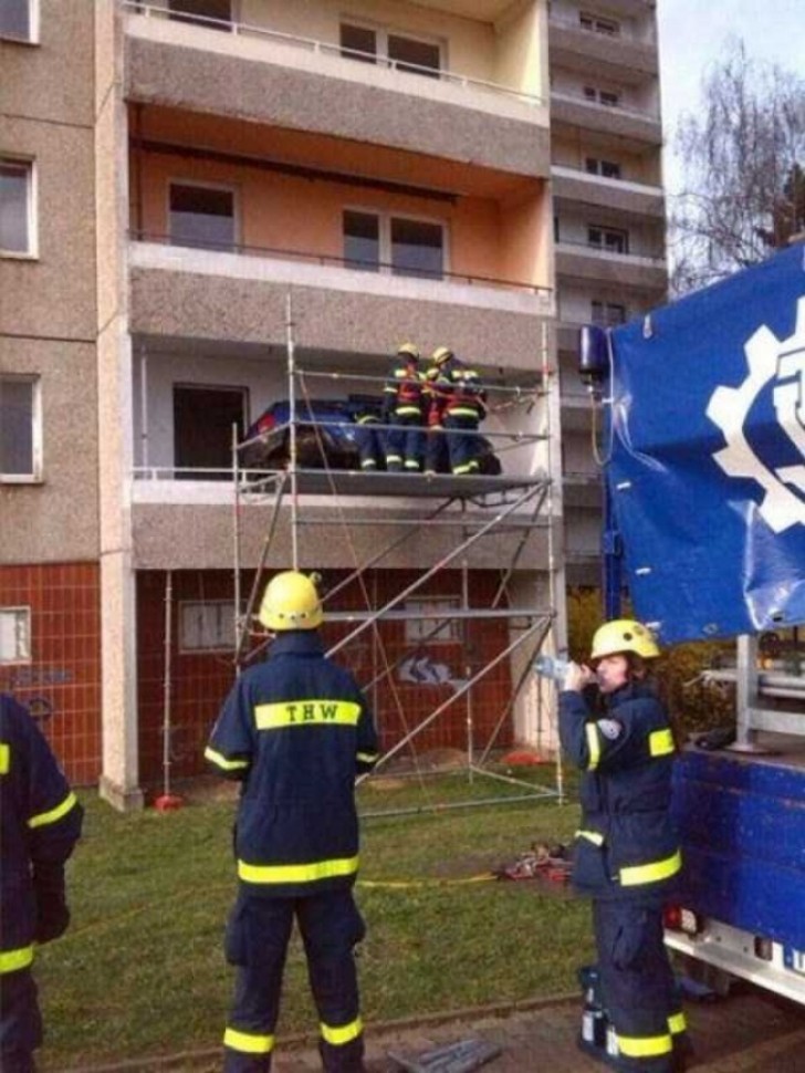 This team of firefighters is pulling a car down from a balcony.
