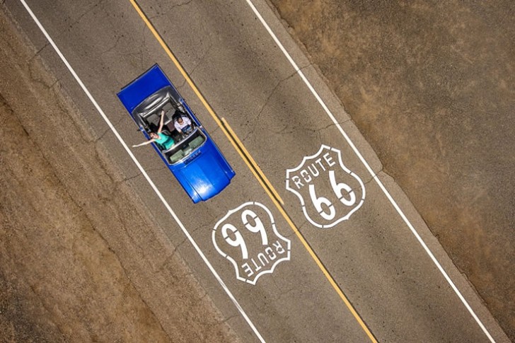 Una coppia a bordo di in una classica Ford Mustang Cabriolet blu che percorre la storica Route 66.