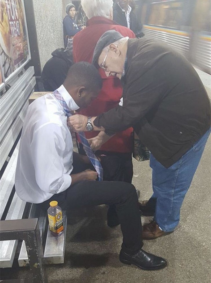 Un hombre anciano ayuda a un joven con dificultad haciendo el nudo de la corbata.