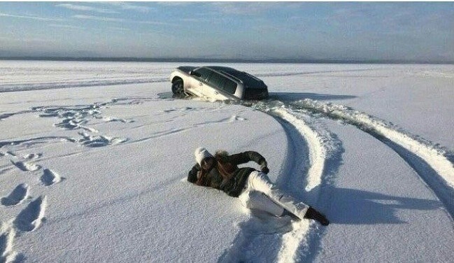 Elle fait la pose et la voiture s'enfonce dans la neige.