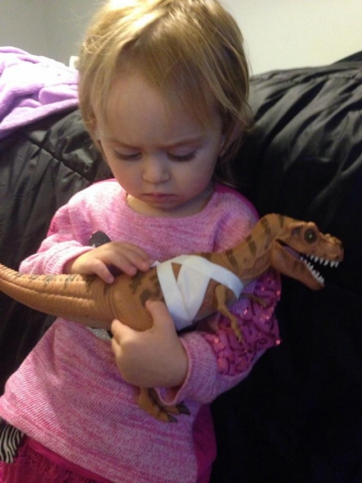 Uma menina de 2 anos que conforta o seu dinossauro ferido.