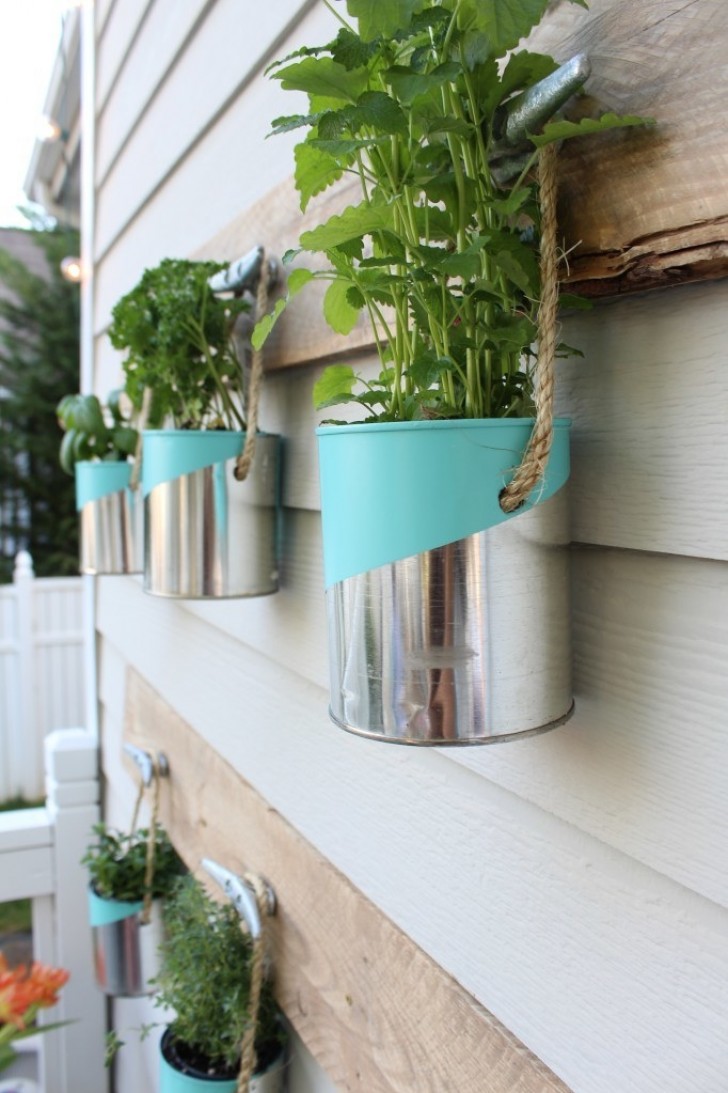 1. Con los envases de lata, una cuerda y un colgante, puedes crear un jardin para colgar en la pared.