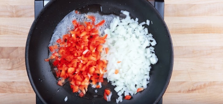 In una padella fate riscaldare l'olio insieme ad una noce di burro, poi inserite la cipolla e il peperone tagliati in pezzi molto piccoli.