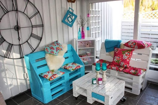 20. A romantic corner on the porch made from wooden pallets and softened by floral cushions.