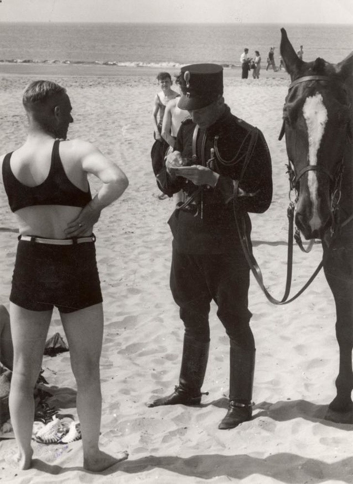 Ein Mann am Strand von Heemskerk erhält eine Strafe für unangemessene Kleidung, Holland, 1931.