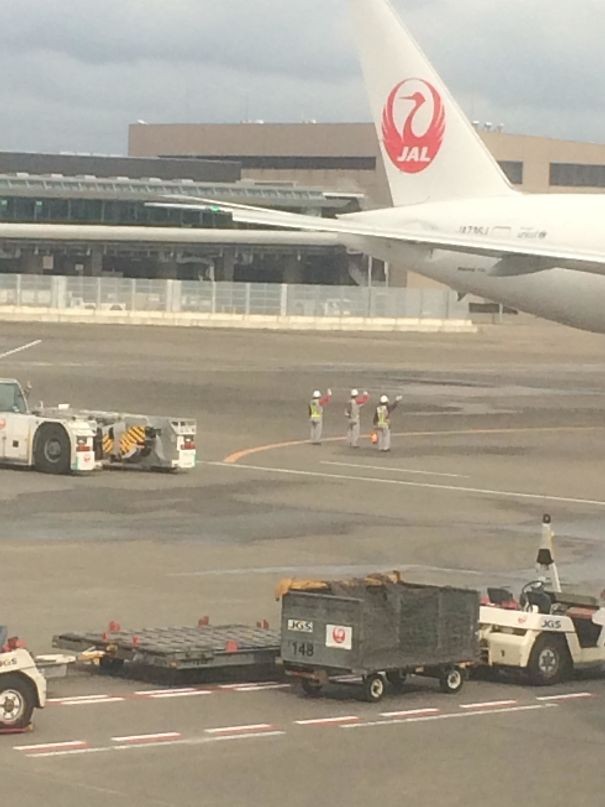 Prima della partenza, gli operatori sulla pista salutano l'aereo in fase di decollo.