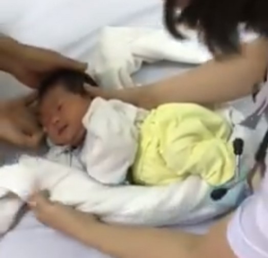 Krankenschwester zeigt Trick, um Neugeborenen mit Hilfe eines Handtuchs und eines großen Tuches schnell in den Schlaf zu helfen - 3