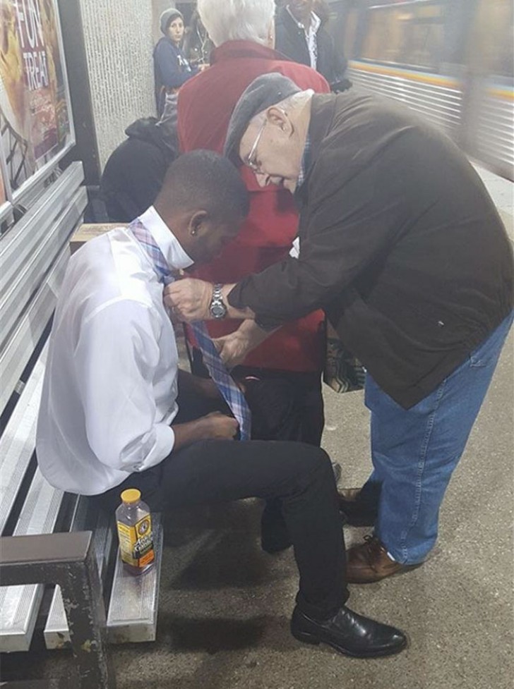 Un anziano aiuta un giovanotto in difficoltà con il nodo alla cravatta.